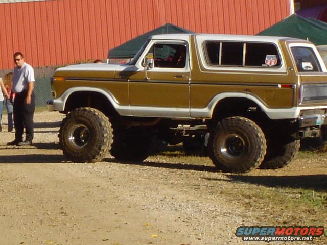 Lifted 1978 Ford Bronco with large off-road tires, gold and white paint