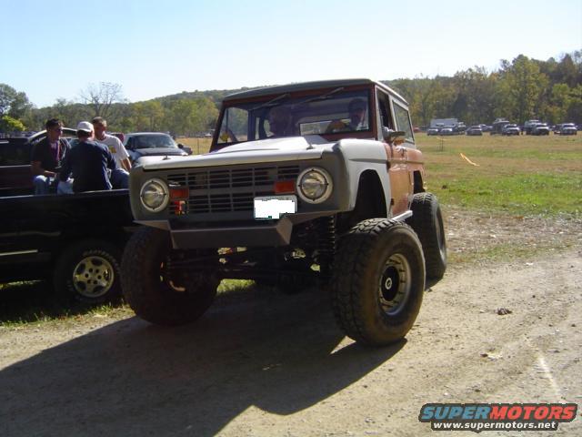 1979 Ford Bronco with aftermarket bumper and large tires parked next to a pickup truck