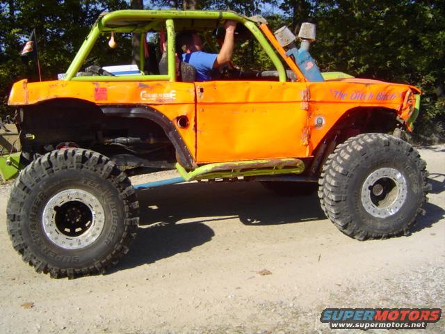 Modified 1979 Ford Bronco with roll cage, large tires, and orange paint. "The Ditch Biker" is written on the door