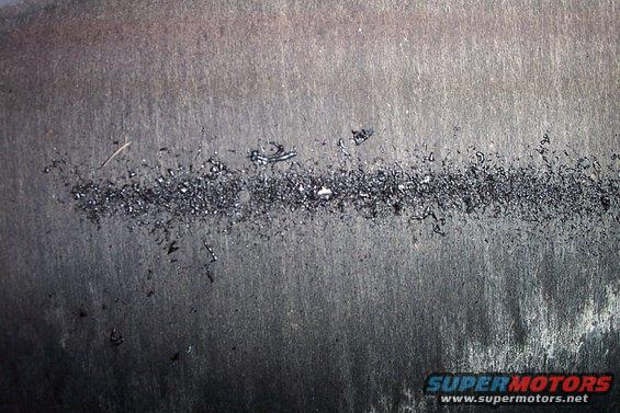 Metal shavings and debris on a dark, textured surface, possibly a tire or brake component