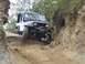 1990 Ford Bronco - A white Jeep Wrangler TJ tackles a challenging off-road obstacle on a dirt path.