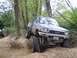 1990 Ford Bronco - Modified Toyota pickup truck tackling a steep, wooded off-road course.