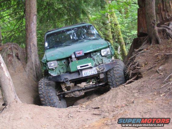 Green off-road vehicle with winch on steep dirt trail