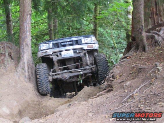 Toyota 4Runner climbing a steep, muddy trail with large tires, front grille visible