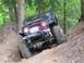 1990 Ford Bronco - This modified off-road vehicle navigates a challenging dirt trail in a forest setting.