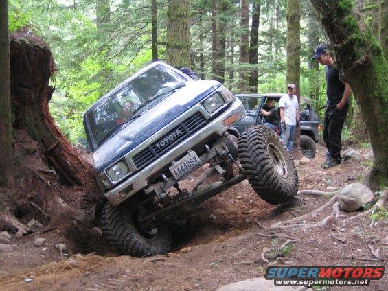 Blue Toyota truck with large tires navigating a steep incline off-road
