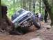 1990 Ford Bronco - A blue Toyota truck is shown attempting a difficult off-road obstacle with another vehicle visible in the background.