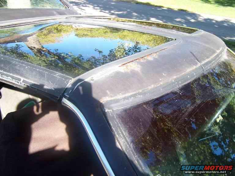 close-up of a car's black vinyl roof with a sunroof, showing some rust and wear