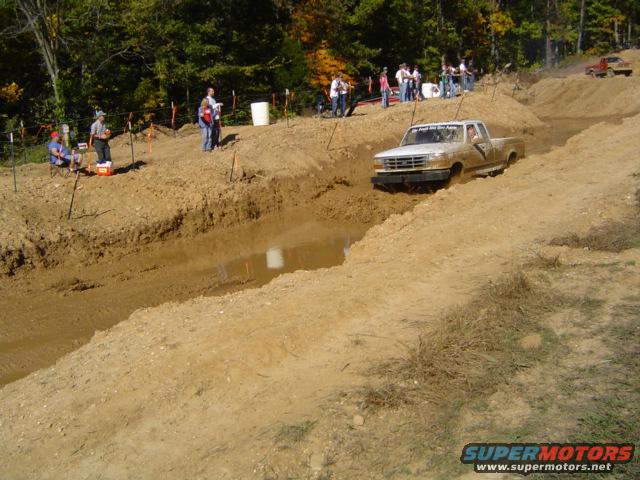 White pickup truck stuck in mud, front grille visible, 1987 model year