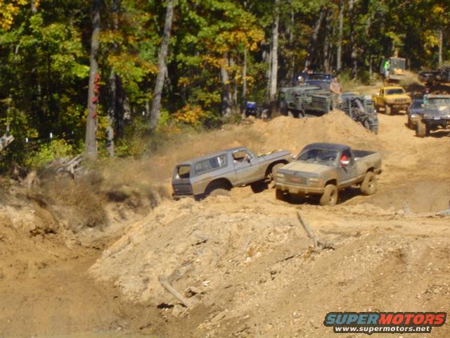Gray 1978 Ford Bronco driving through mud, side view