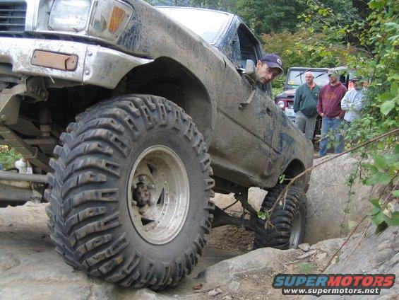 Muddy off-road truck with large tires navigating rocks