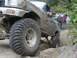 1990 Ford Bronco - This heavily modified truck is shown off-roading with other vehicles in the background.