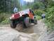 1990 Ford Bronco - Two Jeeps navigate a challenging rocky off-road trail surrounded by trees and hills.
