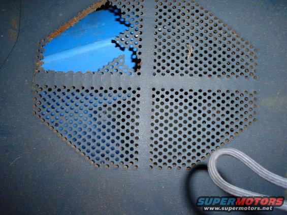 perforated metal vent with blue insulation showing rust and damage