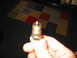 1997 Ford Crown Victoria - A spark plug is shown in a hand, with a patterned rug visible behind it.