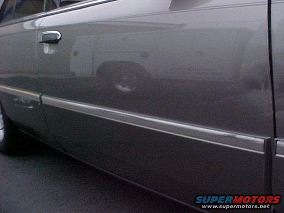 Reflection of a white work van on the side of a dark car