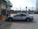 1994 Ford Thunderbird - A silver 1994 Ford Thunderbird is parked in a lot next to a building with a newspaper stand.