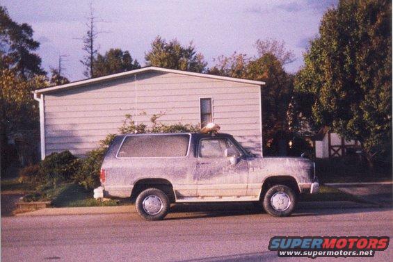Dodge Ramcharger SUV parked on street, side view. House and trees in background