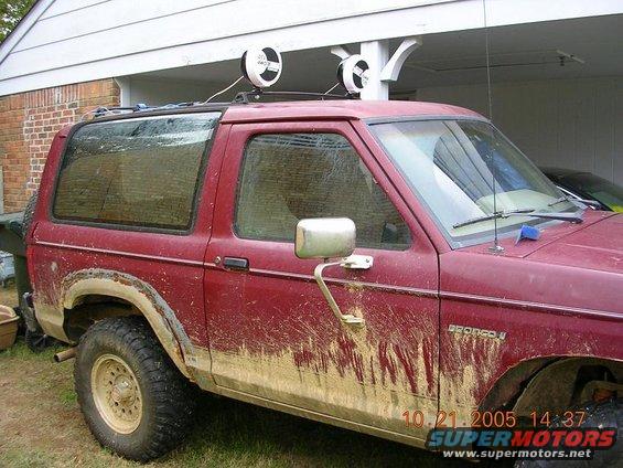 Mud-splattered red 1989 Ford Bronco II parked in front of a garage
