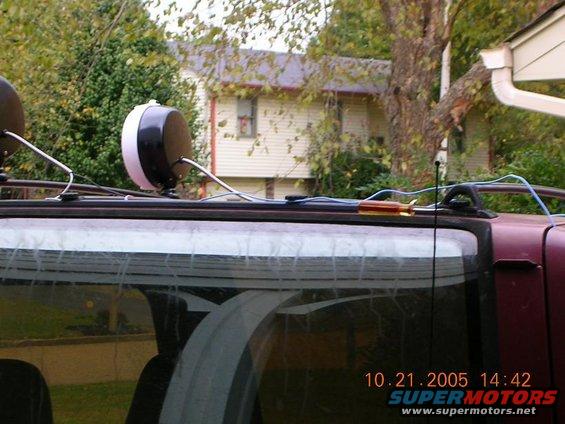 Car roof with two lights, wiring, and a screwdriver on top. House in background