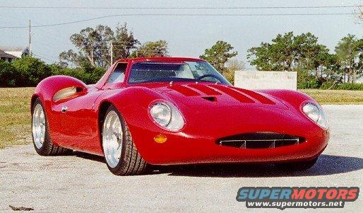 Red sports car with a low profile, rounded body, and prominent hood vents, viewed from a 3/4 front angle