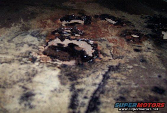 Corroded metal surface with black and brown stains, SuperMotors logo visible