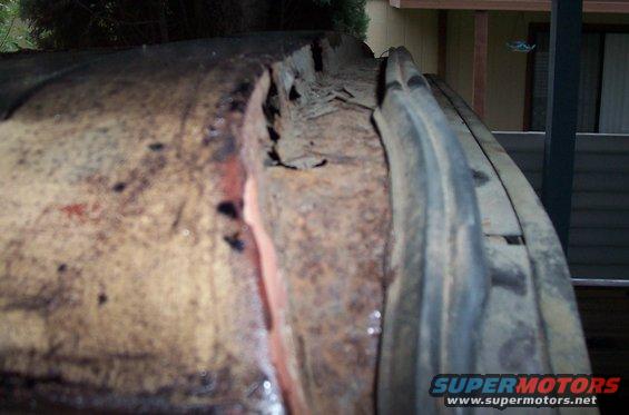 Heavily rusted metal panel with visible damage and peeling paint