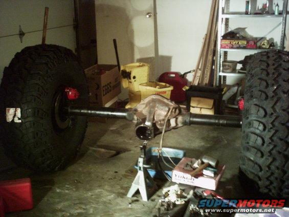 Rear axle assembly with two large tires, one on each end, supported by jack stands