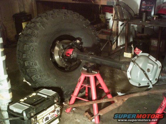 Dana 60 axle with large tire on red jack stands