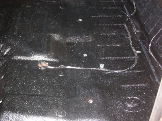 Black textured vehicle floor with visible wiring and mounting points