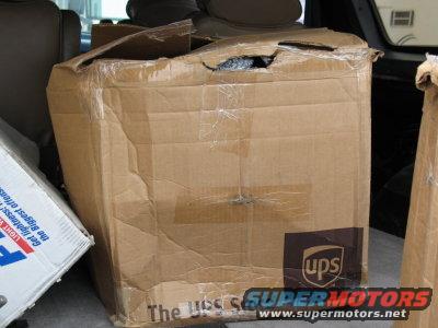 Damaged UPS box and another box in the back of a vehicle