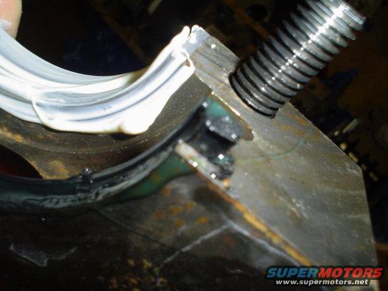Engine bearing being prepped with white sealant and a threaded bolt