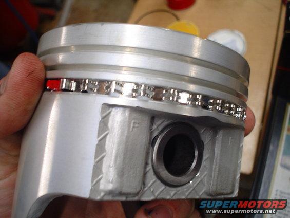 Piston with installed piston rings, one red ring visible