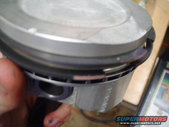 Piston with ring grooves and a wrist pin bore held in a hand