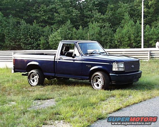 1994 Ford F-150 pickup truck parked on grass next to a road