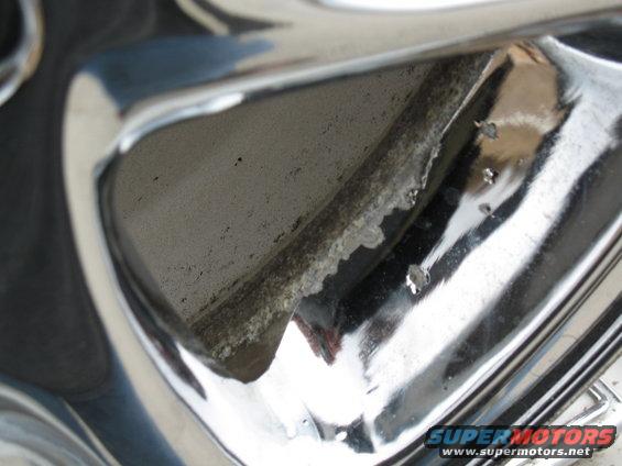 Close-up of a chrome wheel rim showing corrosion and pitting on the inner barrel
