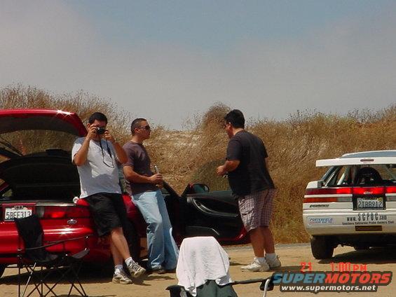 1993 Mazda MX-6 with open trunk and a white race car with spoiler
