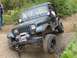 1990 Ford Bronco - A green Jeep Wrangler navigates a rocky off-road trail with a winch attached to the front bumper.