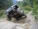 1990 Ford Bronco - An off-road vehicle navigates a challenging rocky terrain on a dirt path.