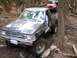 1990 Ford Bronco - Modified Toyota pickup truck with large tires navigating a muddy forest trail, another Jeep visible behind it.