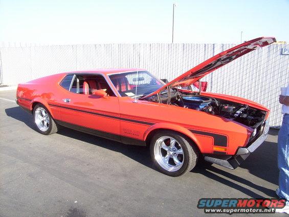 Red classic Mustang with hood open, showing engine. Black stripe along the side