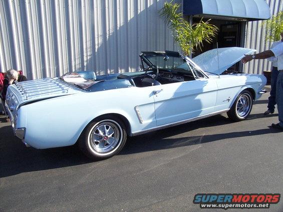 Light blue 1965 Ford Mustang convertible with hood open, viewed from the passenger side 3/4 front