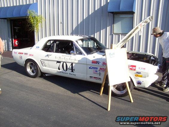 White 1965 Ford Mustang coupe with racing decals and number 704