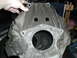 1979 Ford Bronco - A dirty engine block is held by a hand, with a large opening in the center and two square holes above.