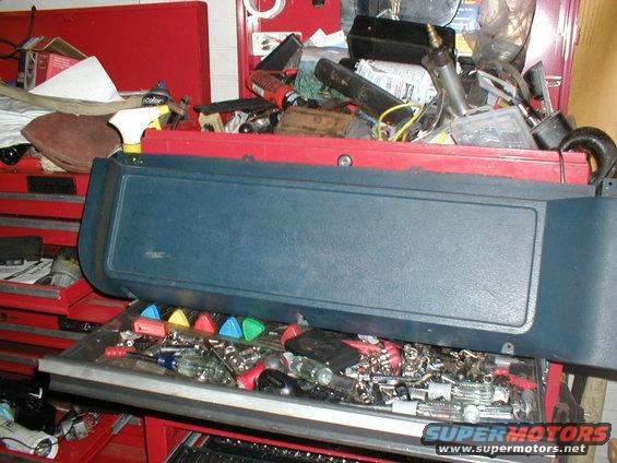 Blue dashboard trim piece resting on an open toolbox filled with tools