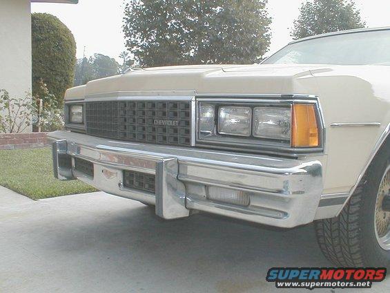 Front of a tan Chevrolet Caprice showing grille with 'CHEVROLET' text, quad headlights, and chrome bumper