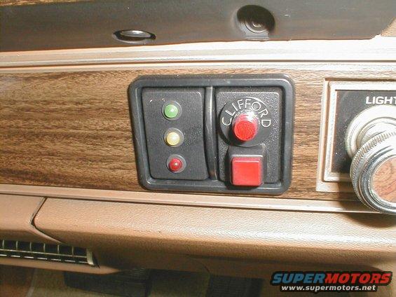 Dashboard with wood grain trim, a Clifford alarm button, and indicator lights
