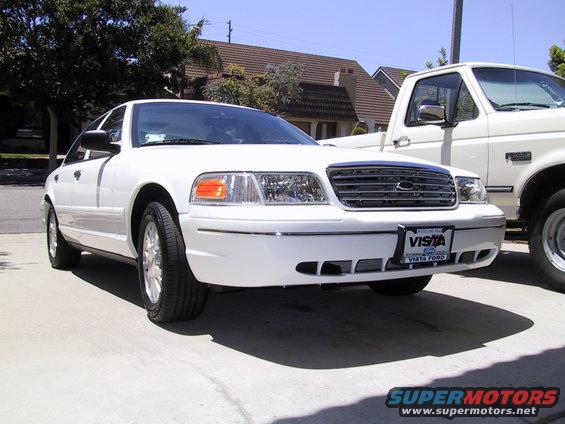 White 2003 Ford Crown Victoria parked in driveway next to a white pickup truck. License plate reads VISTA FORD