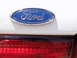 1997 Ford Thunderbird - Close-up of a Ford emblem and a red taillight on a white vehicle.