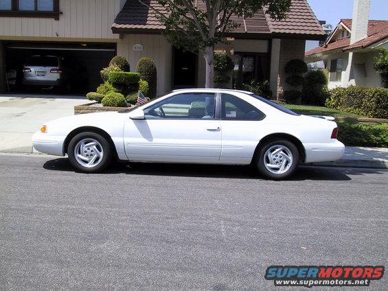 1997 Ford Thunderbird coupe parked on street in front of a house